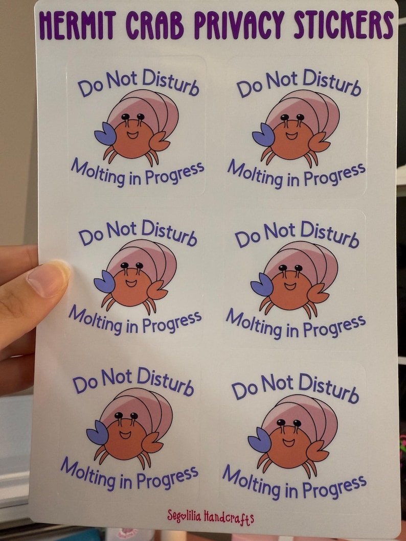 May include: Six white stickers with a cartoon hermit crab on each. The crab is pink and orange with blue claws. The text on each sticker reads "Do Not Disturb Molting in Progress".
