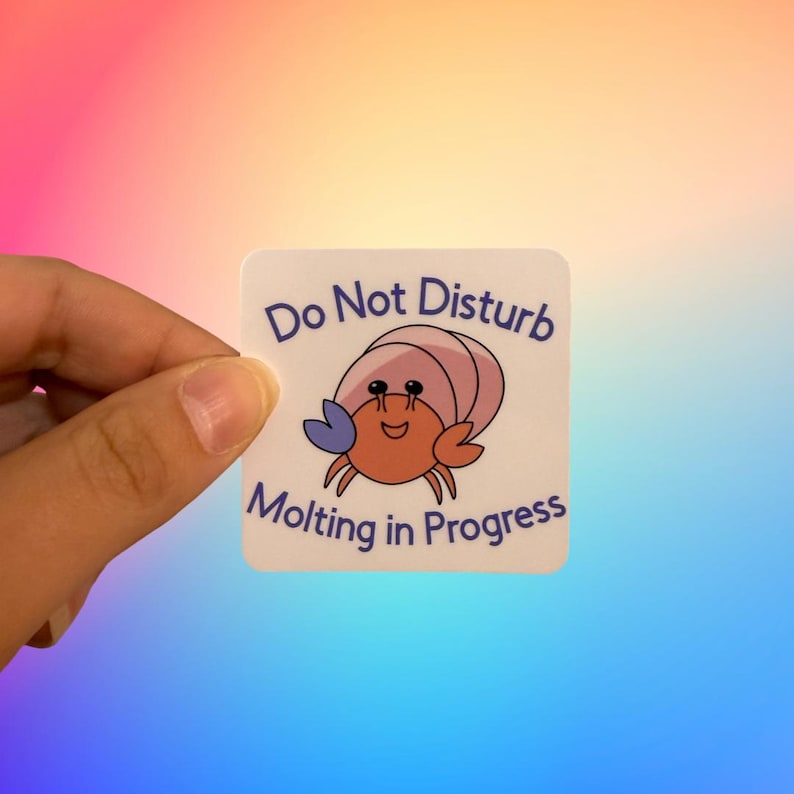 May include: White sticker with the text "Do Not Disturb" and a cartoon hermit crab with a pink shell and blue claws. The text "Molting in Progress" is below the crab.