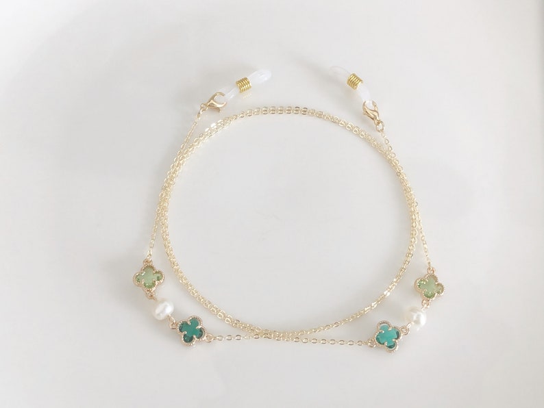 May include: Gold chain glasses retainer with green and white clover charms and white pearl accents.