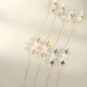 May include: Three gold chains with clear clasps and pearl and crystal accents. Each chain has a different color crystal: yellow, blue, and teal.