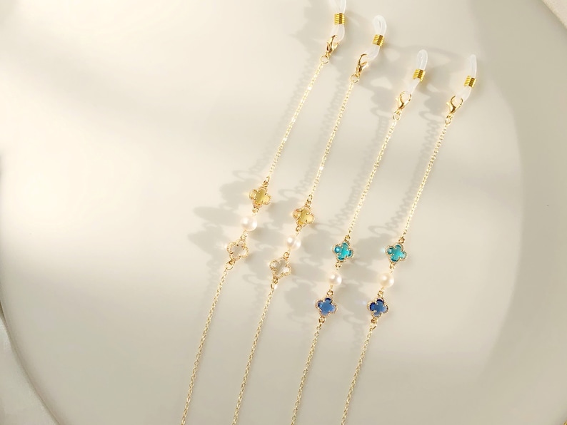 May include: Three gold chains with clear clasps and pearl and crystal accents. Each chain has a different color crystal: yellow, blue, and teal.