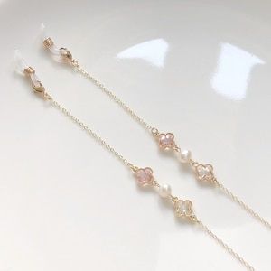 May include: Two gold eyeglass chains with pink and white clover charms and pearl beads.