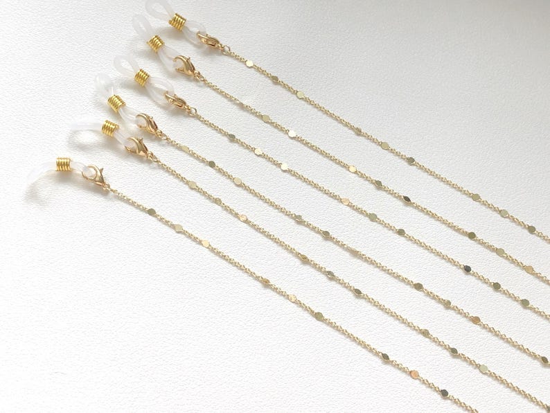 Op de afbeelding: Set van zes gouden oogstrikken met kleine, ronde, platte schakels. Elke ketting heeft aan de uiteinden doorzichtige plastic lussen.