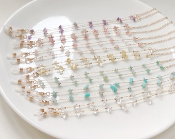 May include: A set of 10 gold chain eyeglass retainers with different colored gemstone beads. The beads are in shades of purple, pink, yellow, green, and clear.