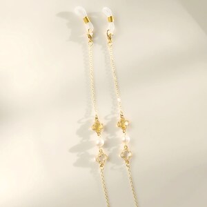 May include: A gold chain with clear and white beads, and clear and gold clover charms. The chain has clear plastic loops at the ends for attaching to glasses.