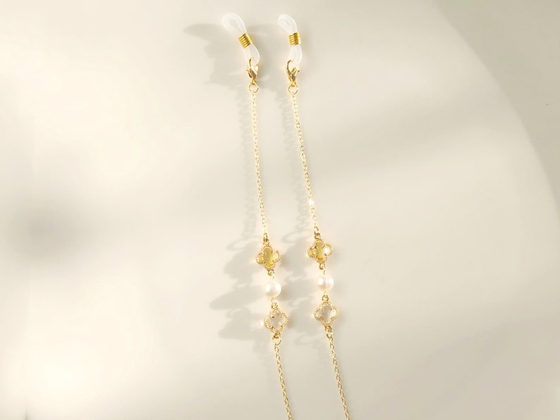 May include: A gold chain with clear and white beads, and clear and gold clover charms. The chain has clear plastic loops at the ends for attaching to glasses.