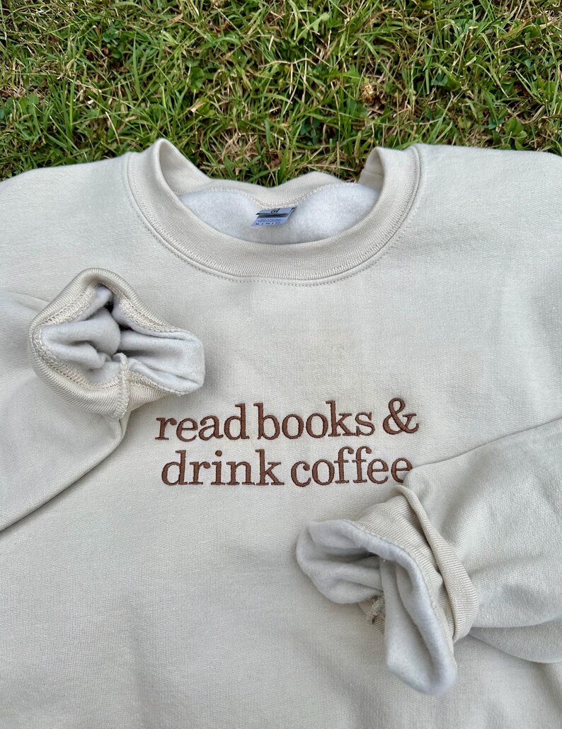 May include: A beige sweatshirt with the text "read books & drink coffee" embroidered in brown on the front.