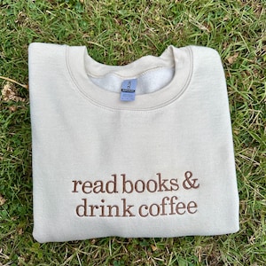 May include: A beige sweatshirt with the text "read books & drink coffee" embroidered in brown on the front.
