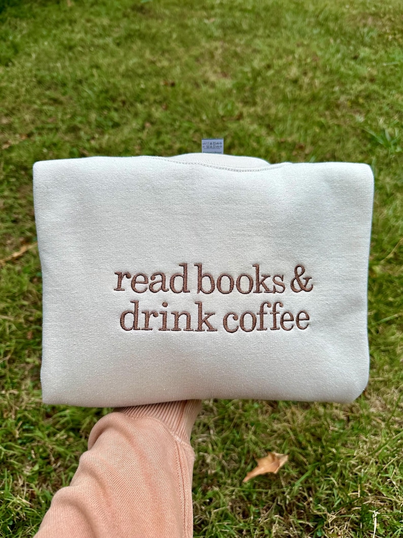 May include: A white sweatshirt with the text "read books & drink coffee" embroidered in brown on the front.