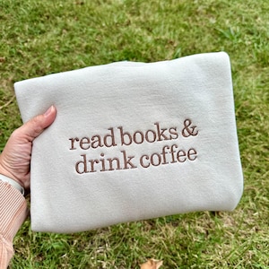 May include: A white sweatshirt with the text "read books & drink coffee" embroidered in brown.