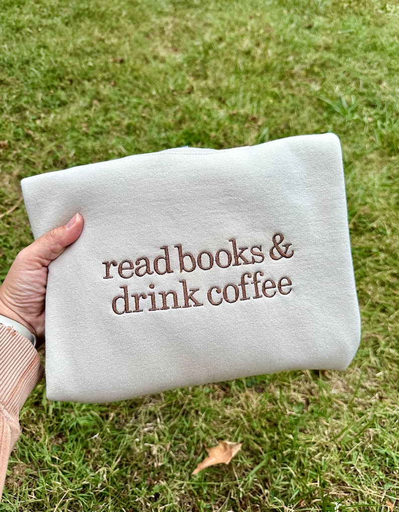 May include: A white sweatshirt with the text "read books & drink coffee" embroidered in brown.