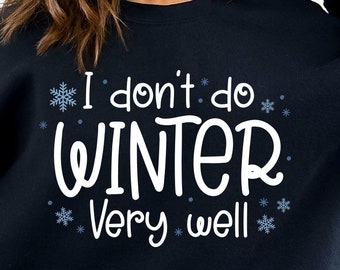 Puede incluir: Una sudadera negra con el texto "I don't do winter very well" en blanco con detalles de copos de nieve azules.