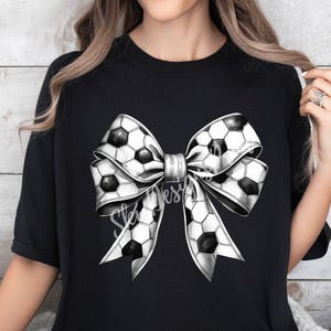 Puede incluir: Camiseta negra con un gran lazo blanco y negro en forma de bal&oacute;n de f&uacute;tbol. El lazo est&aacute; hecho de tela con estampado de bal&oacute;n de f&uacute;tbol.