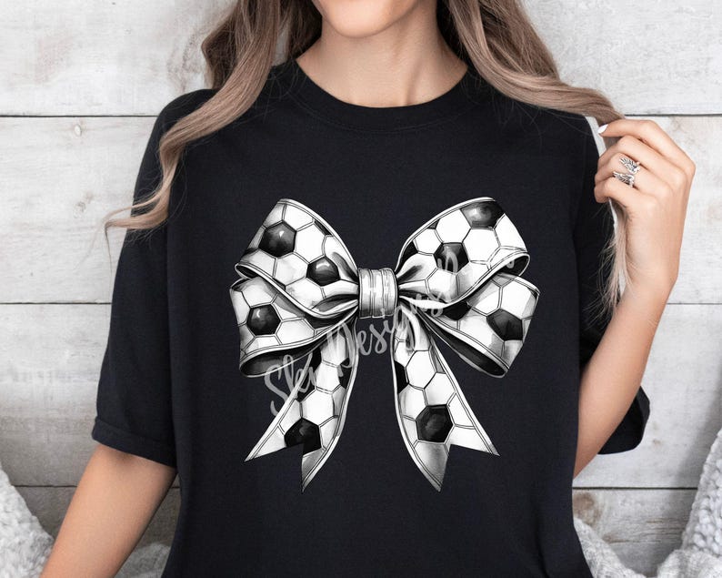 Puede incluir: Camiseta negra con un gran lazo blanco y negro en forma de bal&oacute;n de f&uacute;tbol. El lazo est&aacute; hecho de tela con estampado de bal&oacute;n de f&uacute;tbol.
