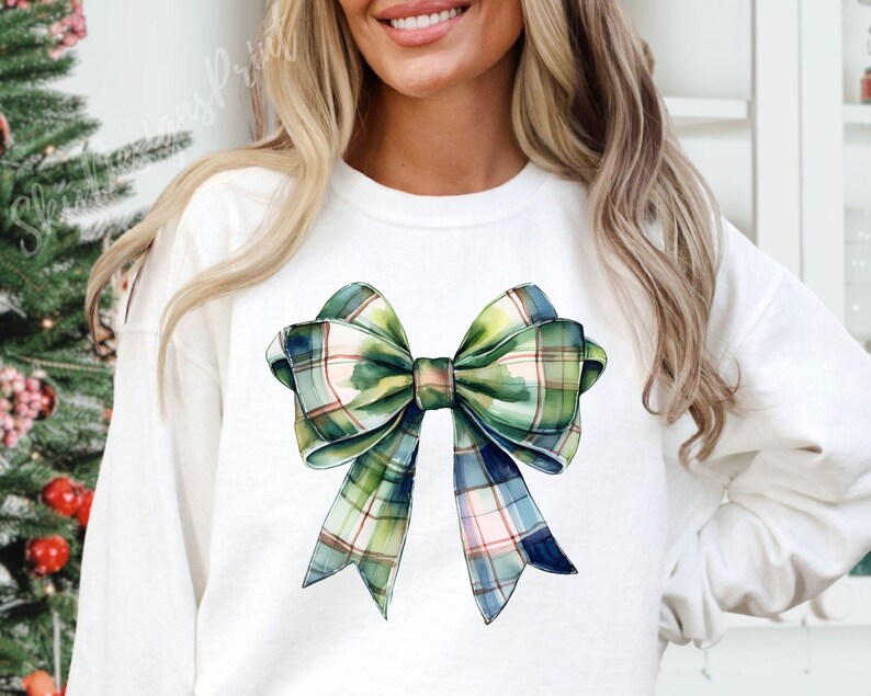 Peut inclure: Sweat-shirt blanc orn&eacute; d'un grand n&oelig;ud aquarelle. Le n&oelig;ud pr&eacute;sente un motif &agrave; carreaux dans les tons de vert, de bleu et de rose. Le motif est centr&eacute; sur le devant du haut &agrave; manches longues, cr&eacute;ant un look festif et &eacute;l&eacute;gant.