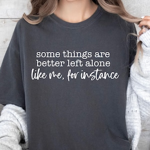 Puede incluir: Camiseta gris oscuro con el texto blanco: "some things are better left alone like me, for instance". Una camiseta informal y cómoda para el uso diario.