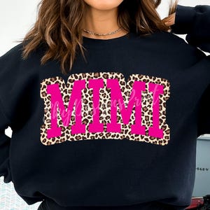 Pu&ograve; includere: Felpa nera con una grafica rosa "MIMI" su uno sfondo leopardato.
