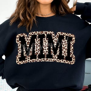 Pu&ograve; includere: Felpa nera con una grande grafica "MMM" in un design a stampa leopardata.