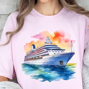 May include: A pink t-shirt with a watercolor illustration of a cruise ship sailing on a blue ocean with a sunset in the background.