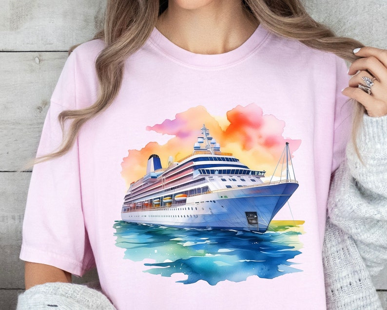 May include: A pink t-shirt with a watercolor illustration of a cruise ship sailing on a blue ocean with a sunset in the background.