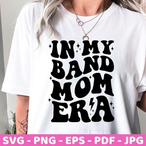 Pu&ograve; includere: Maglietta bianca con testo nero che recita "In My Band Mom Era" in un font retr&ograve;.