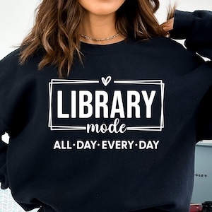Puede incluir: Sudadera negra con texto blanco que dice "Library mode all day every day" con un símbolo de corazón sobre la palabra "Library".