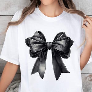 May include: A white t-shirt with a large black bow printed on the front. The bow is made of satin and has a slightly textured look.