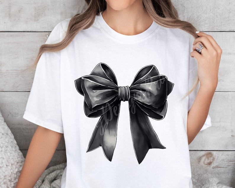 May include: A white t-shirt with a large black bow printed on the front. The bow is made of satin and has a slightly textured look.