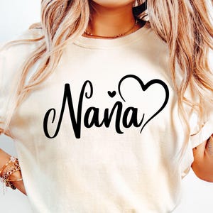Puede incluir: Camiseta blanca con la palabra "Naina" en letras cursivas negras y un dise&ntilde;o de coraz&oacute;n negro.