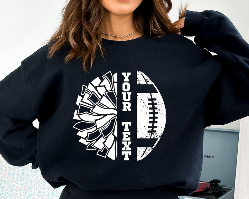 May include: Black sweatshirt with a white graphic of a cheerleading pom-pom and a football with the text "YOUR TEXT".