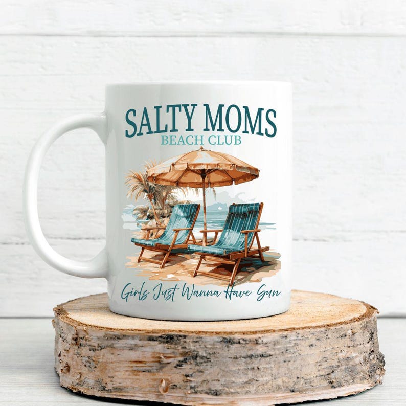 May include: White ceramic mug with a blue and white illustration of beach chairs under a beach umbrella. The text "Salty Moms Beach Club" and "Girls Just Wanna Have Sun" are printed on the mug.