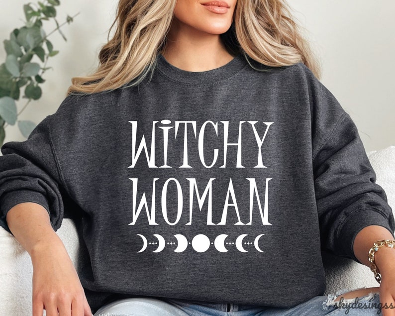 May include: A dark gray sweatshirt with the text "Witchy Woman" in white lettering and a row of white crescent moons below the text.