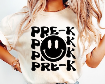 May include: White t-shirt with a black smiley face and the text "PRE-K" repeated around it.