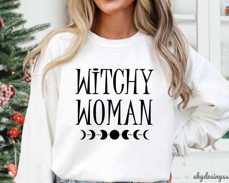 May include: White sweatshirt with the text "Witchy Woman" and a row of crescent moons printed in black.
