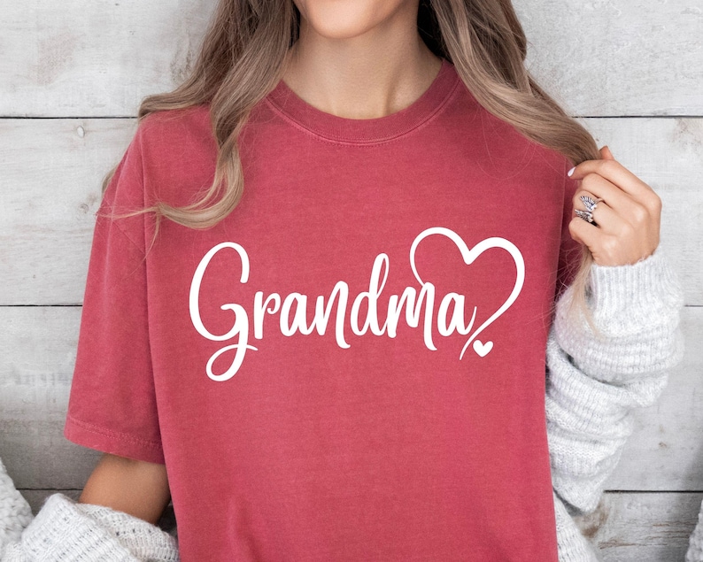 May include: A red t-shirt with the word "Grandma" in white cursive lettering and a white heart design.