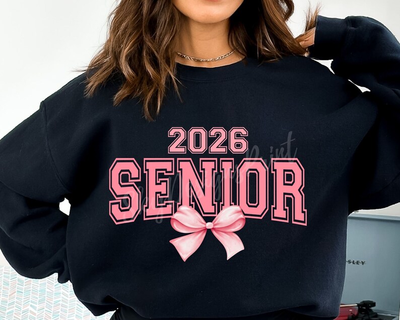 May include: Black sweatshirt with pink text that says "2026 Senior" with a pink bow underneath.