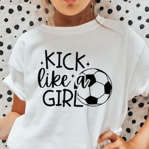 Op de afbeelding: Wit T-shirt met de tekst "KICK like a GIRL" in zwart en een zwart-witte voetbalafbeelding. Het shirt heeft een ronde hals.