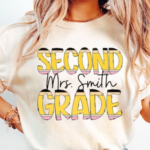 May include: A white t-shirt with the text "Second Grade" in yellow and black letters with a pencil design. The text "Mrs. Smith" is in black letters below the main text.