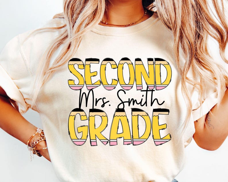 May include: A white t-shirt with the text "Second Grade" in yellow and black letters with a pencil design. The text "Mrs. Smith" is in black letters below the main text.