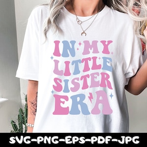 May include: White t-shirt with a pink and blue graphic that says "In My Little Sister Era".