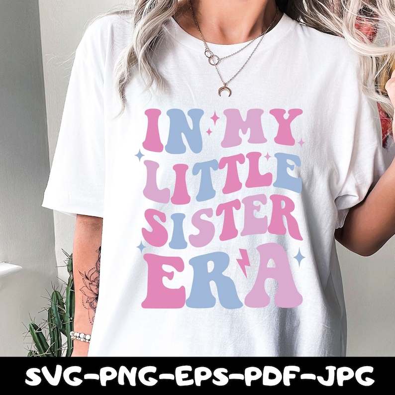 May include: White t-shirt with a pink and blue graphic that says "In My Little Sister Era".