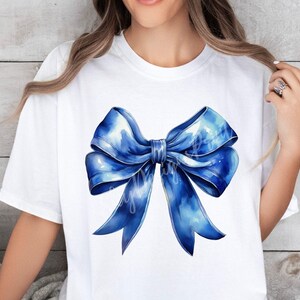 May include: A white t-shirt with a large blue watercolor bow design.
