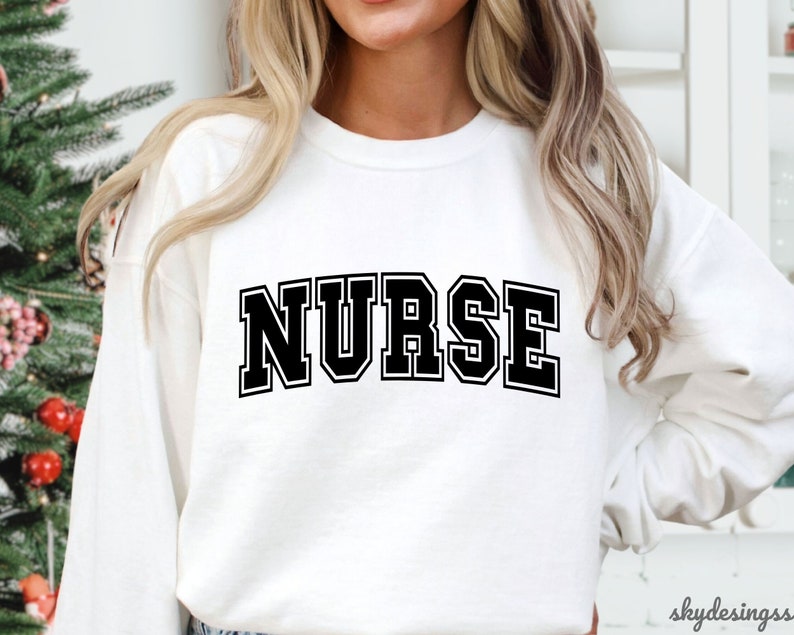 May include: White sweatshirt with black text that reads "NURSE" in a collegiate font.
