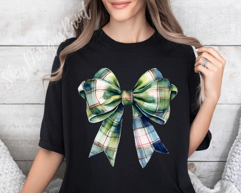 Peut inclure: T-shirt noir avec un motif de n&oelig;ud &eacute;cossais &agrave; l'aquarelle dans les tons de vert, bleu et rose. Le n&oelig;ud est le point central, avec des ombrages d&eacute;taill&eacute;s et un aspect r&eacute;aliste. Le t-shirt a un col rond classique et des manches courtes.