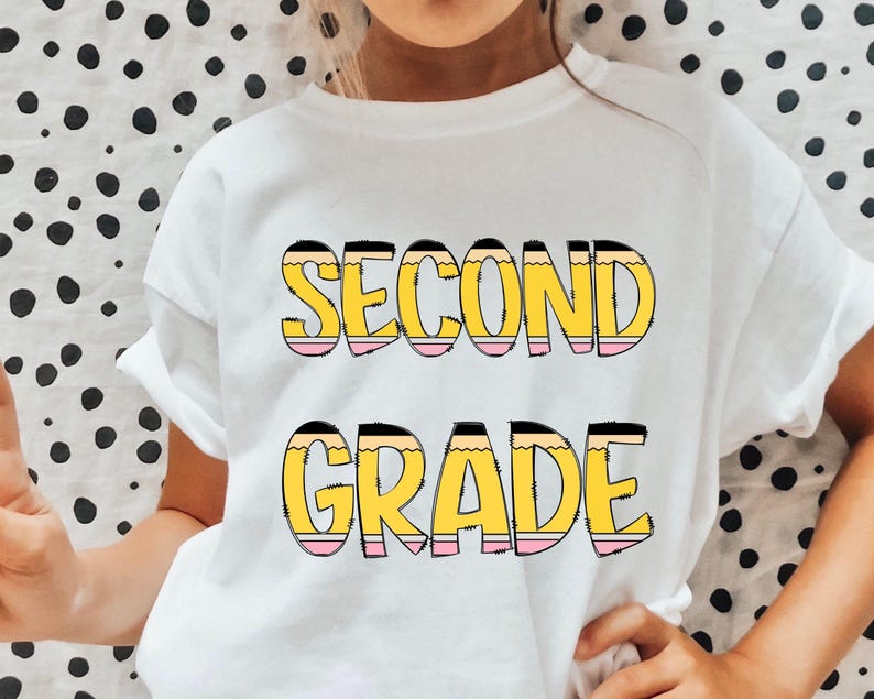 May include: White t-shirt with the words "Second Grade" in yellow and pink letters that look like pencils.