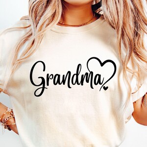 May include: White t-shirt with black text that says "Grandma" with a heart design.