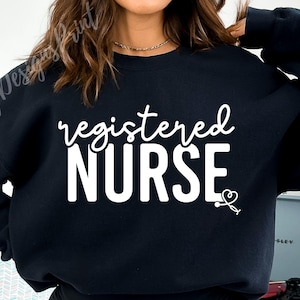 Könnte beinhalten: Schwarzer Pullover mit weißem Text, der "registered NURSE" lautet, mit einem kleinen weißen Herz und einer Stethoskopgrafik.