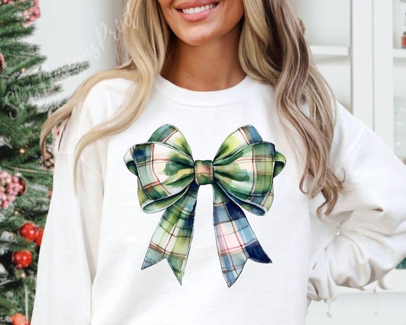 Peut inclure: Sweat-shirt blanc orn&eacute; d'un grand n&oelig;ud aquarelle &agrave; carreaux verts, bleus et roses. Le n&oelig;ud est l'&eacute;l&eacute;ment central du design, rendu avec un d&eacute;tail artistique. Le sweat-shirt est de style d&eacute;contract&eacute; et confortable.