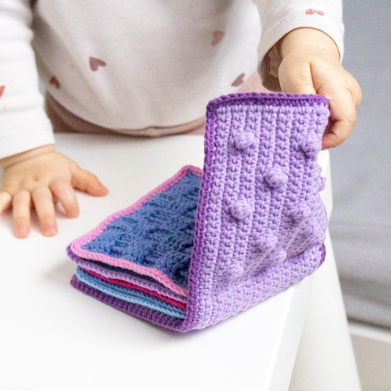 Baby playing with a handmade crochet sensory book created from a detailed crochet pattern, designed for sensory exploration and fine motor development.