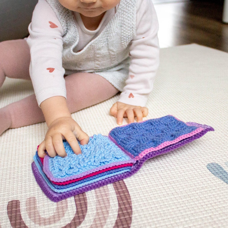 Child enjoying a sensory book crafted from a crochet pattern, an ideal handmade educational toy for babies.